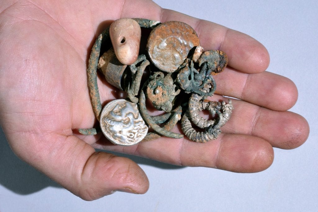 A general picture of the cache of silver objects: two coins of Alexander of Macedon, three rings, four bracelets, two decorated earrings, three other earrings (probably made of silver) and a small stone weight. (Photo: Clara Amit/ IAA)