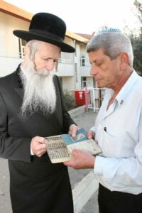 Rabbi Grossman receiving the parchment from Mr. Dotan. (Photo: Courtesy Migdal Ohr)