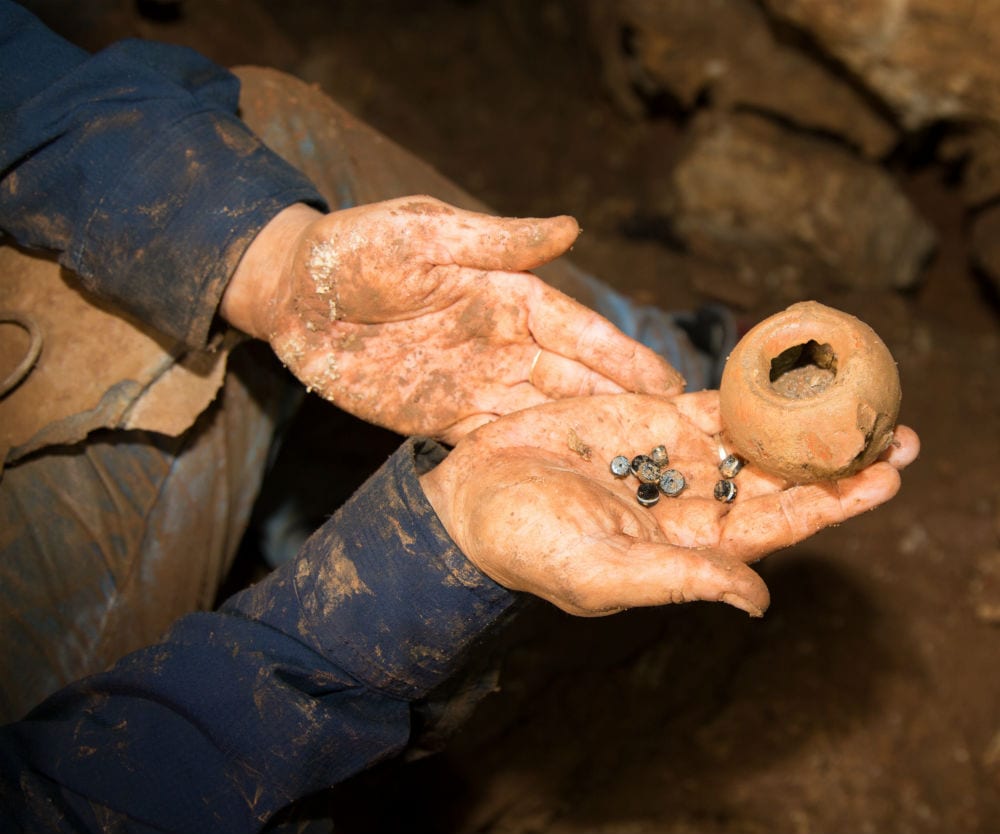 A photograph taken in the cave: agate stones that were part of a string of beads and the Hellenistic oil lamp in which the stones were kept. (Photo: Shmuel Magal/ IAA)