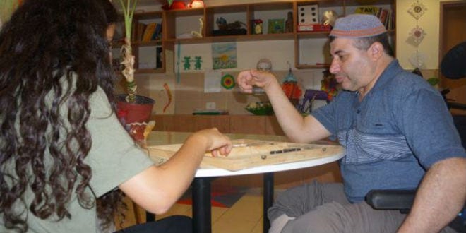 A patient at Colel Chabad's Grabski Center in Migdal HaEmek sits with his caregiver. (Photo: Colel Chabad)