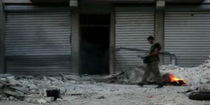 Soldier walking among rubble in Aleppo, Syria. (Photo: Voice of America News: Scott Bobb reports from Aleppo, Syria/ Wiki Commons)