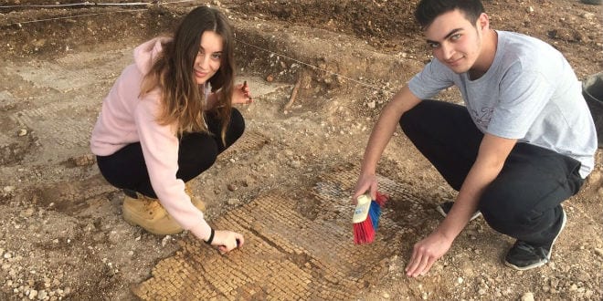High school students in the excavation at Shlomi clean a mosaic that they discovered at the site. (Photo: Karen Covello-Paran/Israel Antiquities Authority)