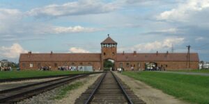 The main gate at the former Nazi concentration camp of Auschwitz II (Birkenau), and the railroad tracks leading up to it. (Photo: Michel Zacharz /Wikimedia Commons)