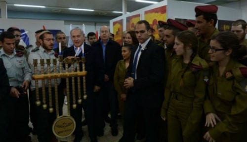 Prime Minister Benjamin Netanyahu lights the menorah with members of the IDF and Defense Minister Moshe Ya'alon on the first night of Hanukkah. (Photo: Amos Ben Gershom/ GPO)