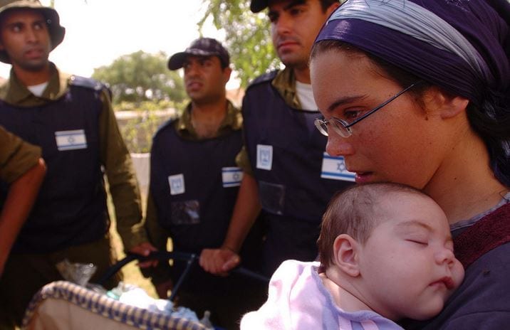 IDF soldiers accompany a mother and her child as they are relocated during the evacuation of the Israeli community Bedolach in 2005. (Photo: IDF)