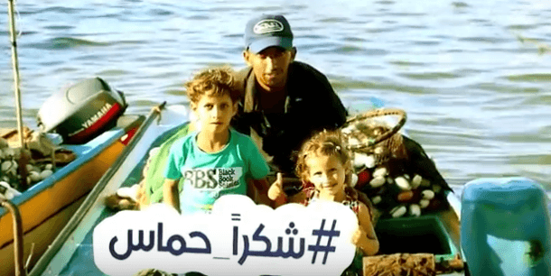 A Gazan family holds a sign reading #Thank You Hamas. (Video Screenshot)