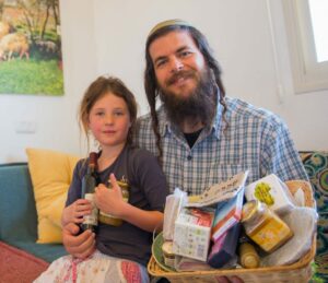 Nati Rom, founder of Lev HaOlam in his home with his daughter and one of the packages getting ready to be sent out. (Photo: Hillel Maeir/TPS)