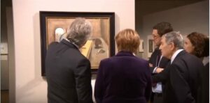 German Chancellor Angela Merkel (center) at an exhibit of Holocaust art on January 25, 2016. (Photo: YouTube)