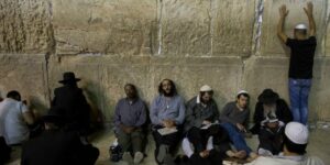 Orthdox Jewish men sit in mourning for the destruction of the Temple on Tisha B'Av at the Wall Western in the Old City of Jerusalem. (Yonatan Sindel/Flash90)