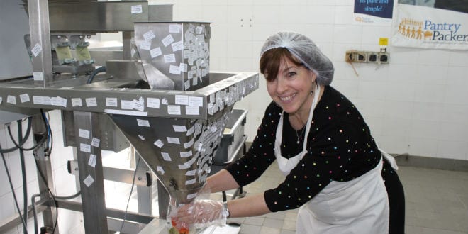 Tsivya Fox, Director of Client Relations at Breaking Israel News packages rice for underprivileged families at Colel Chabad's Pantry Packers in Jerusalem (Photo: Breaking Israel News)